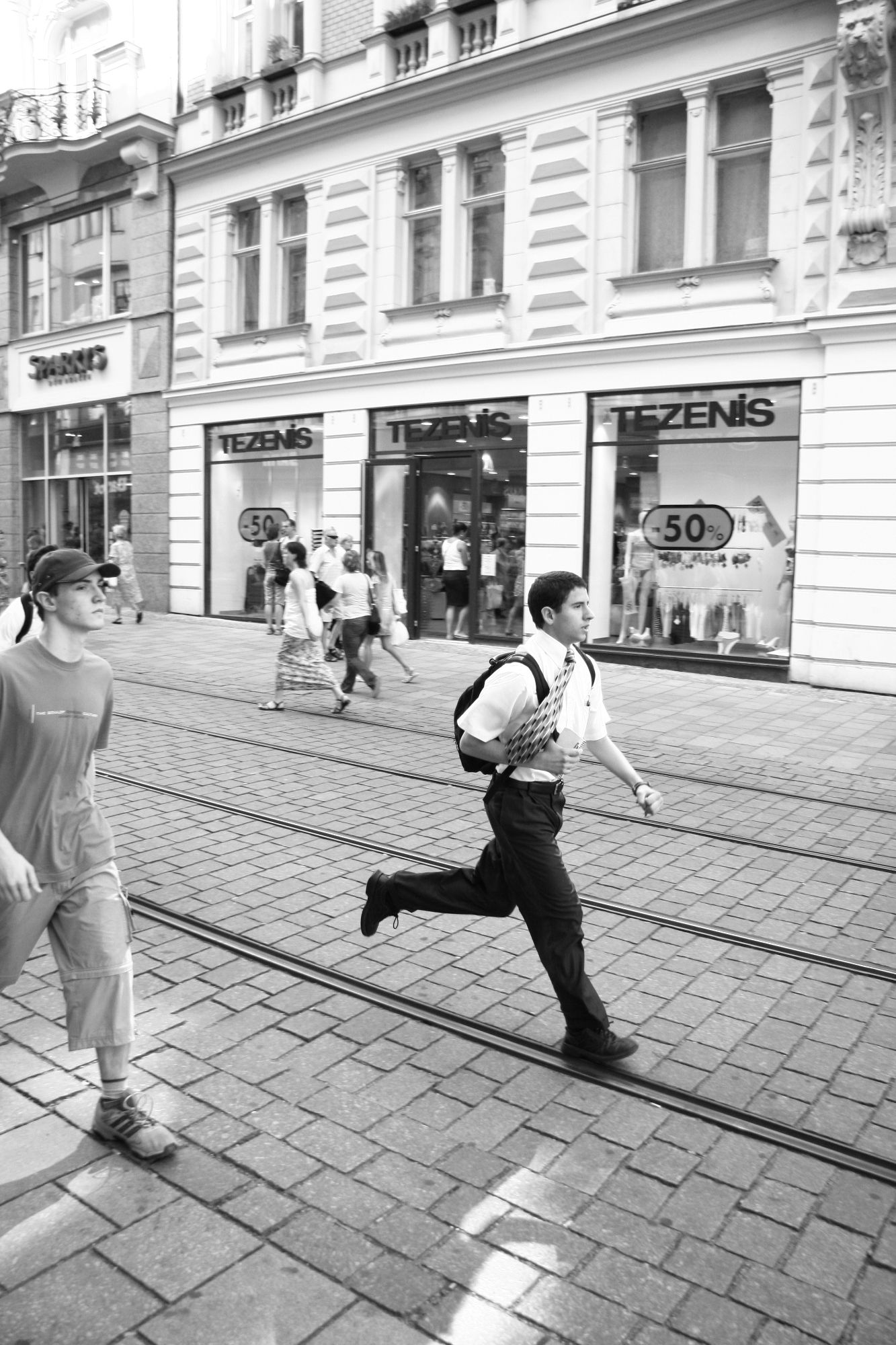Black and white photo of young man running down the street in Brno Czech republic 